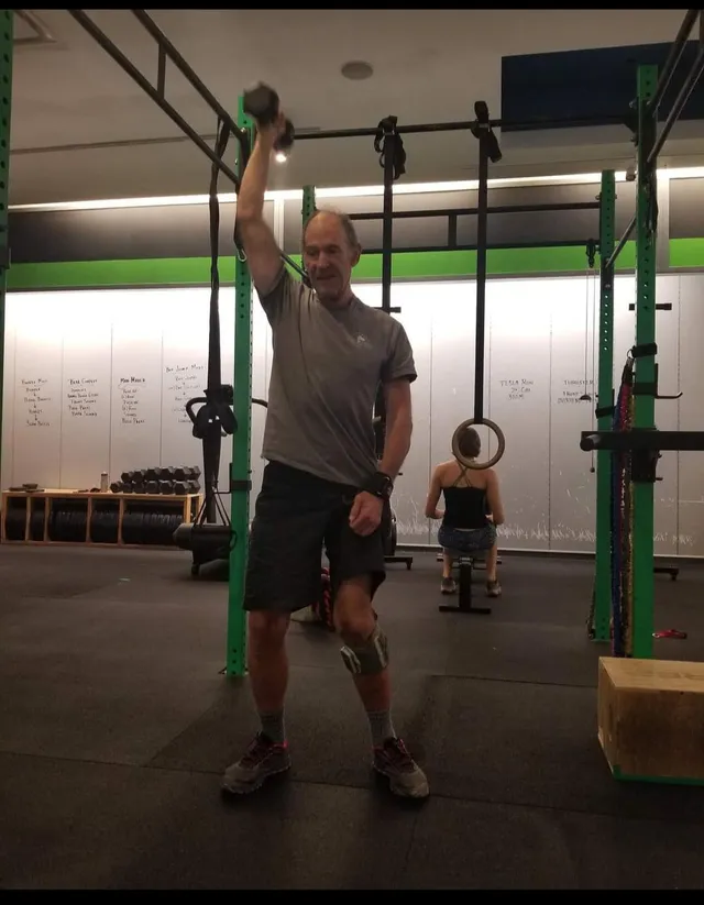 An athlete presses a dumbbell overhead with one arm during a training session